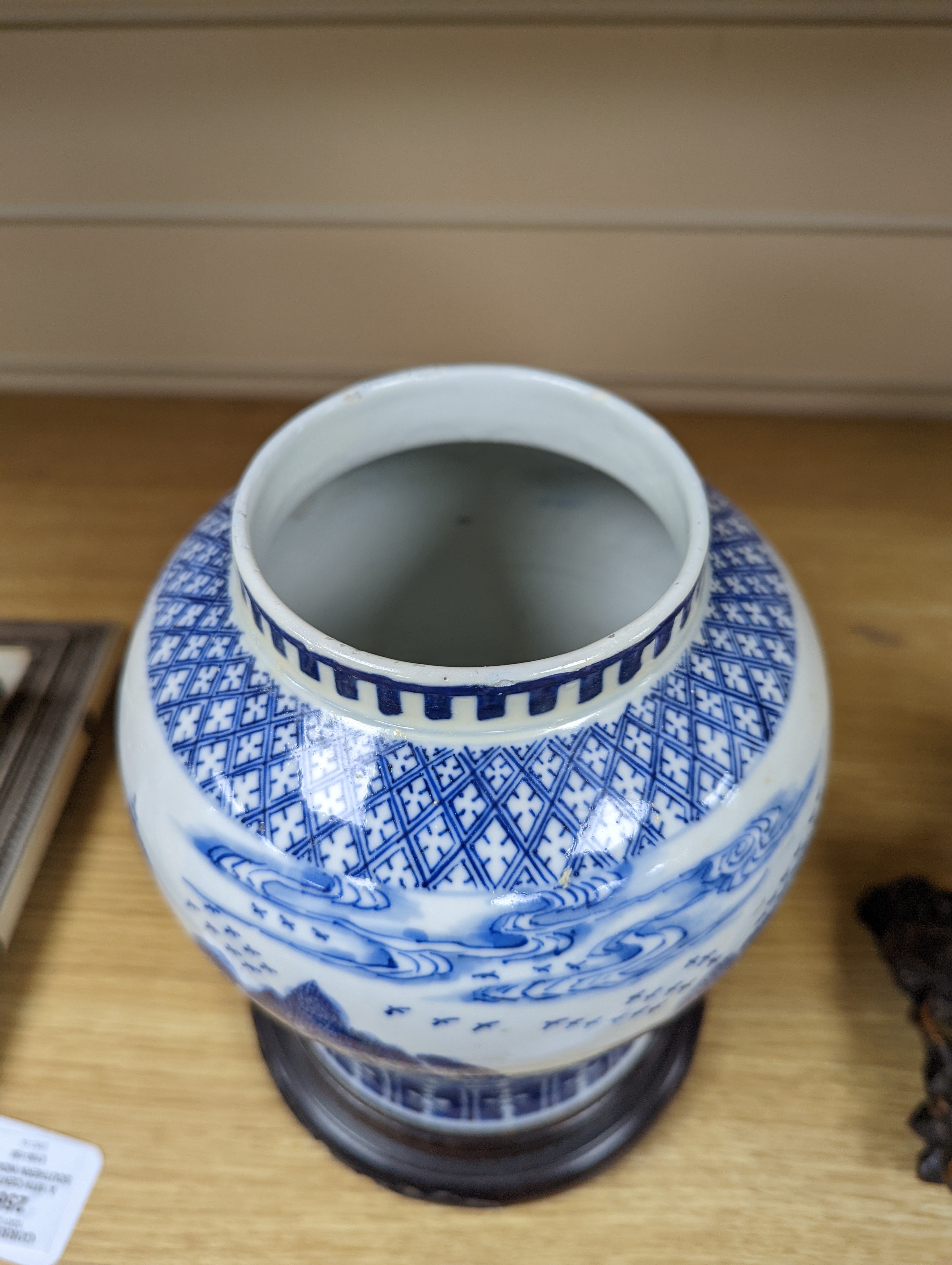 A late 19th / early 20th century Chinese blue and white landscape jar and cover, wood stand 30cm total height
